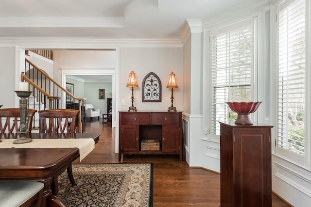 living area with dark wood-style floors, a decorative wall, stairs, and crown molding