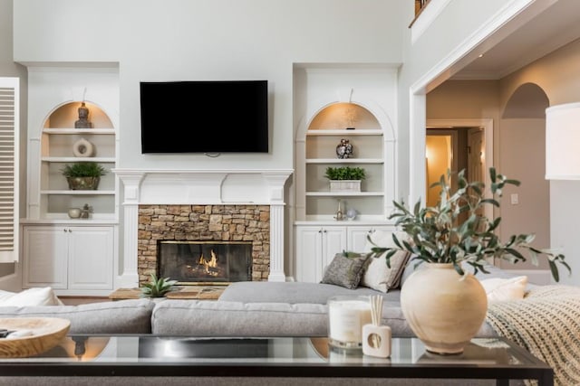 living area with built in shelves and a stone fireplace