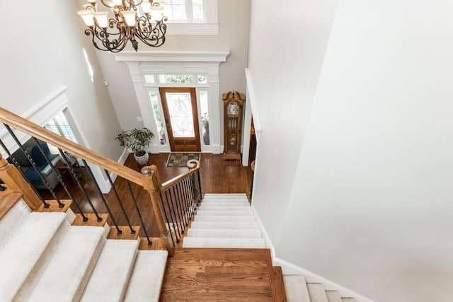 foyer featuring a notable chandelier, stairway, a high ceiling, wood finished floors, and baseboards