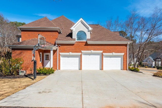 traditional-style house featuring an attached garage, concrete driveway, brick siding, and a shingled roof