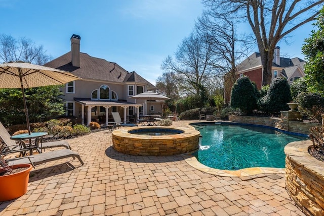 pool featuring an in ground hot tub and a patio area