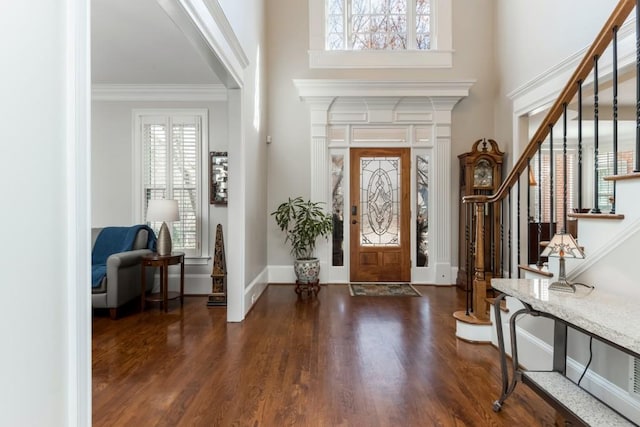 entryway with baseboards, a towering ceiling, dark wood-style flooring, stairs, and crown molding