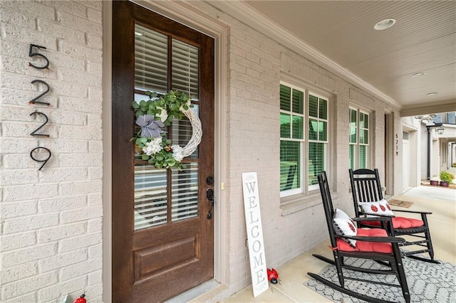 doorway to property with covered porch and brick siding