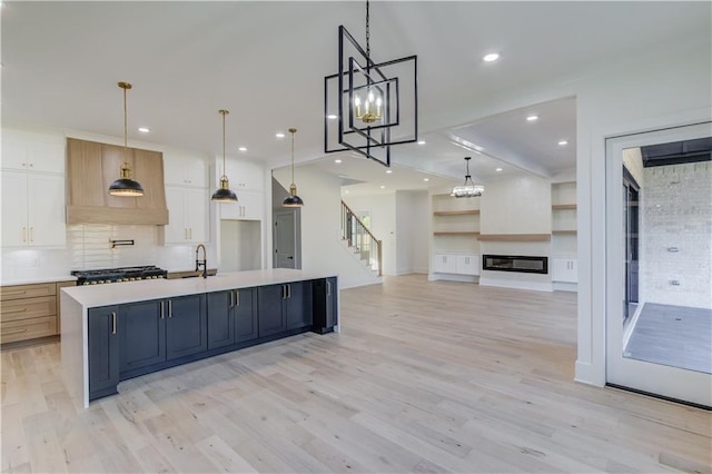 kitchen with light hardwood / wood-style floors, a spacious island, white cabinetry, and hanging light fixtures