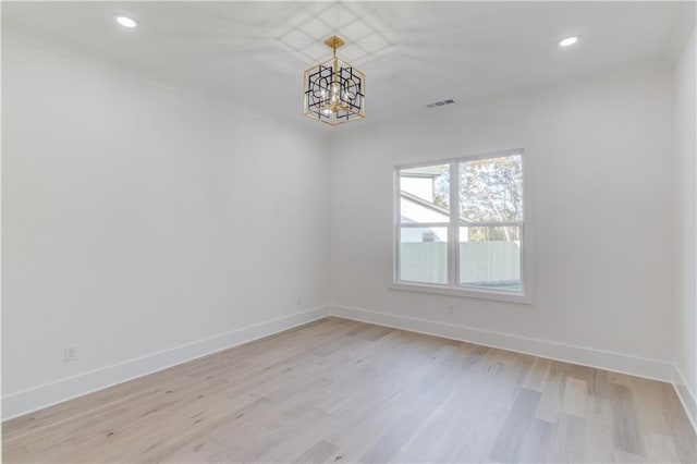 unfurnished room with light wood-type flooring and an inviting chandelier