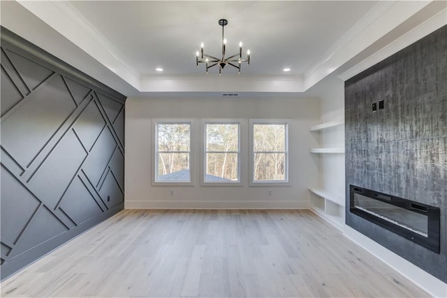 unfurnished living room with a large fireplace, light hardwood / wood-style floors, crown molding, and a tray ceiling