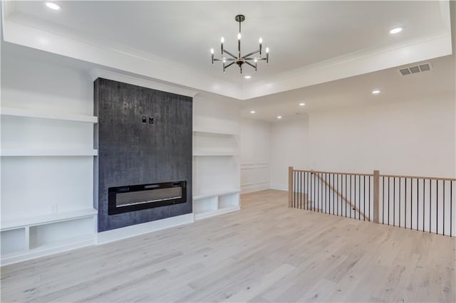 unfurnished living room featuring a notable chandelier, light hardwood / wood-style floors, built in features, and a fireplace