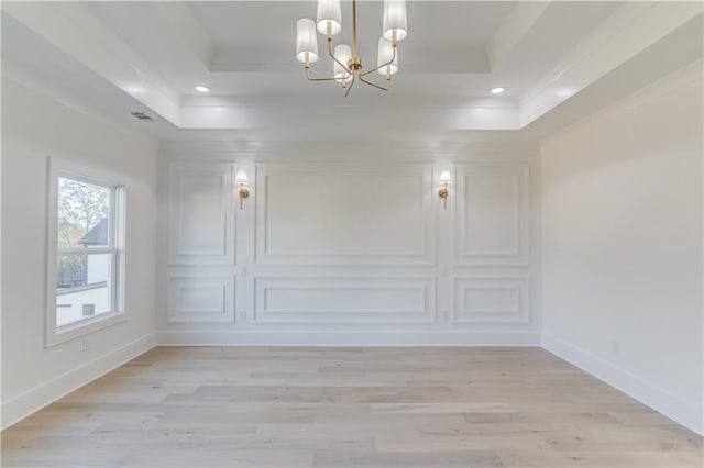 unfurnished room featuring a notable chandelier, a raised ceiling, crown molding, and light hardwood / wood-style flooring