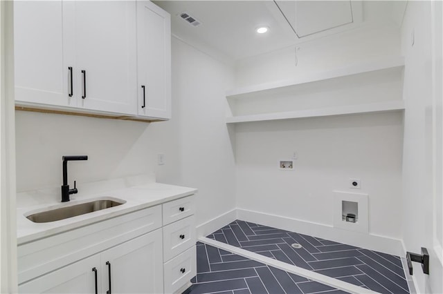 laundry area with electric dryer hookup, cabinets, dark tile patterned flooring, sink, and washer hookup