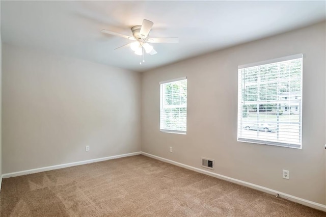 unfurnished room with a ceiling fan, light carpet, and baseboards