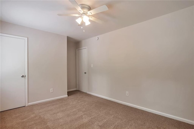 carpeted spare room with ceiling fan and baseboards