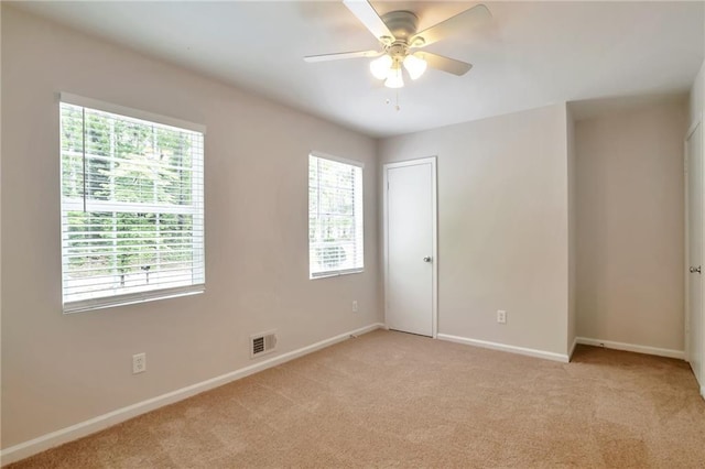 unfurnished room with light colored carpet, ceiling fan, and baseboards