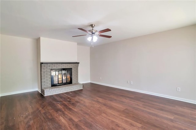 unfurnished living room with dark wood-type flooring, a ceiling fan, baseboards, and a brick fireplace