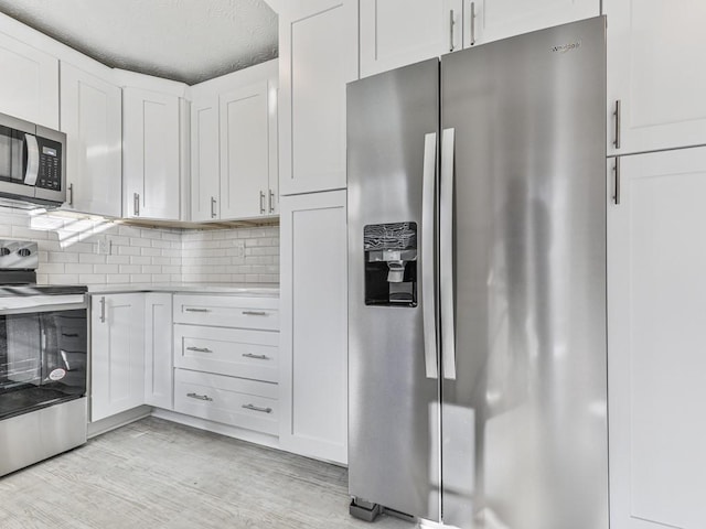 kitchen with backsplash, a textured ceiling, stainless steel appliances, light hardwood / wood-style floors, and white cabinetry