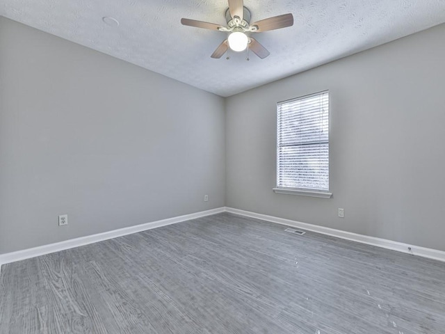 empty room featuring a textured ceiling, ceiling fan, and dark wood-type flooring