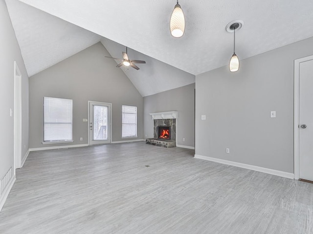 unfurnished living room featuring ceiling fan, a high end fireplace, high vaulted ceiling, and light wood-type flooring