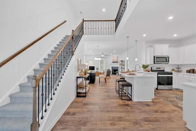 2703 Jordan Ln, Lithia Springs, GA 30122 - kitchen with appliances with stainless steel finishes, a breakfast bar area, open floor plan, an island with sink, and white cabinets
