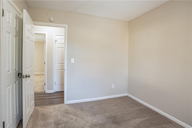 carpeted empty room featuring a textured ceiling