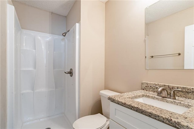 bathroom featuring a textured ceiling, toilet, vanity, and walk in shower