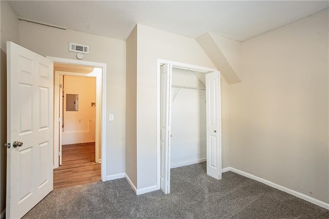 unfurnished bedroom featuring electric panel, a closet, and dark carpet