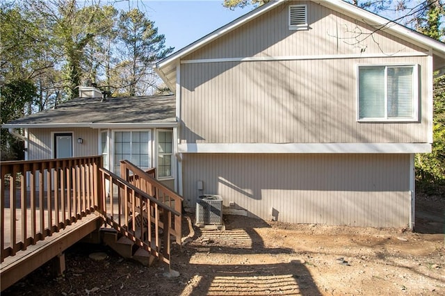 rear view of property featuring central AC unit and a wooden deck