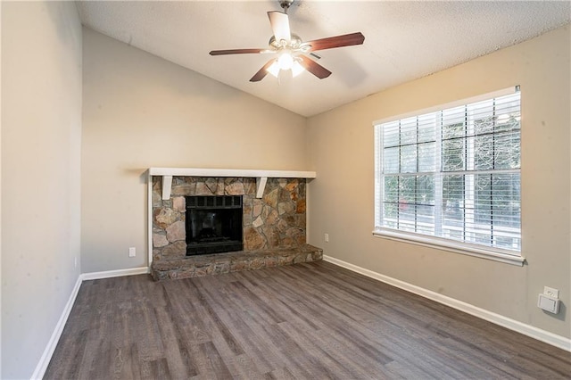 unfurnished living room featuring ceiling fan, a stone fireplace, dark wood-type flooring, and lofted ceiling