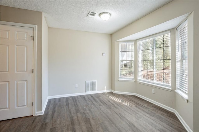 spare room with dark hardwood / wood-style floors and a textured ceiling