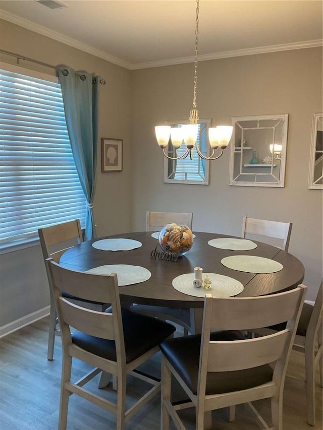 dining space with hardwood / wood-style flooring, crown molding, and an inviting chandelier