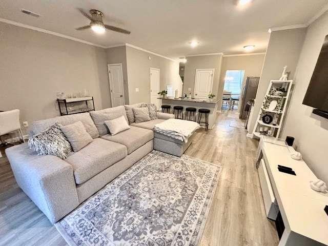 living room featuring ceiling fan, light hardwood / wood-style flooring, and crown molding