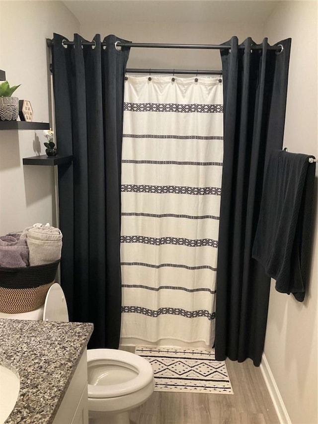 bathroom featuring toilet, a shower with shower curtain, hardwood / wood-style flooring, and vanity