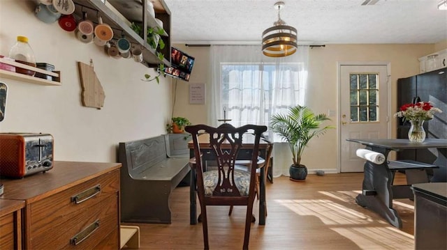 dining space with a chandelier, a textured ceiling, baseboards, and wood finished floors