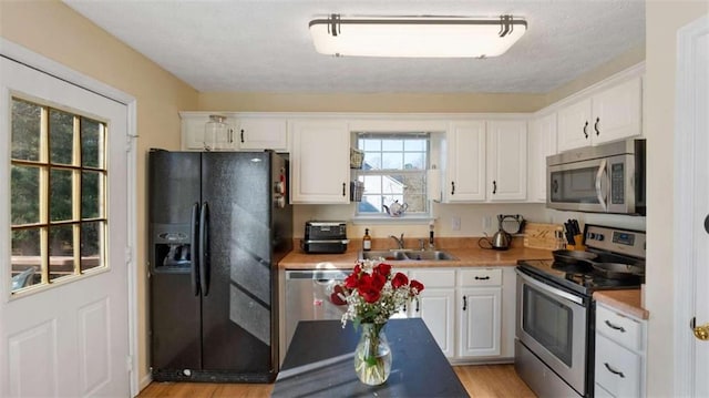 kitchen with a sink, appliances with stainless steel finishes, and white cabinetry