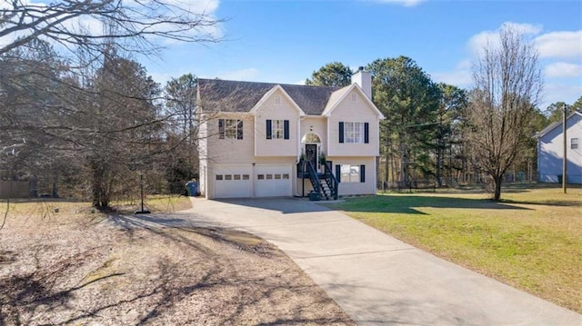 split foyer home featuring a garage, driveway, a chimney, and a front yard