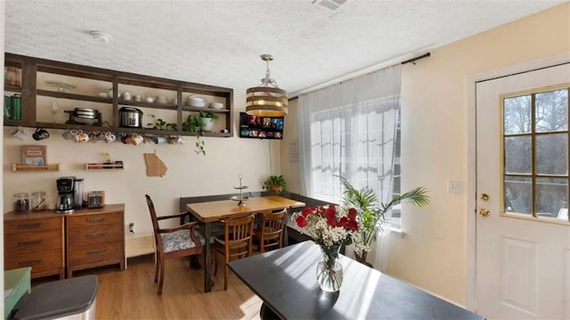 dining space with light wood-style flooring and a textured ceiling