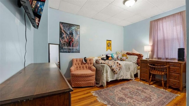 bedroom featuring a drop ceiling and wood finished floors