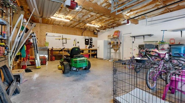 garage featuring a workshop area, a garage door opener, and white fridge with ice dispenser