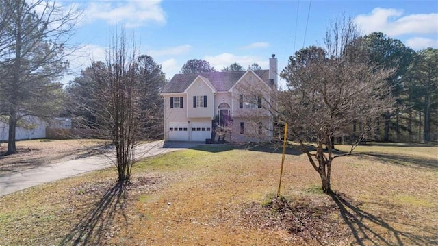 view of front facade with concrete driveway, a chimney, a garage, and a front lawn