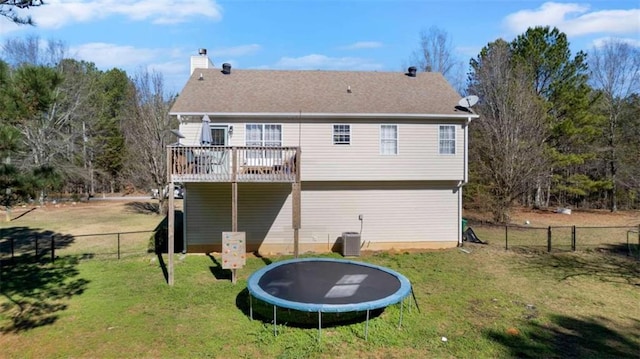 rear view of property with a fenced backyard, a chimney, central air condition unit, a trampoline, and a lawn