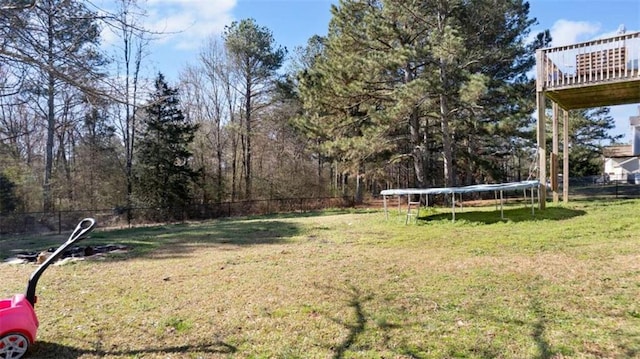 view of yard with a trampoline and fence