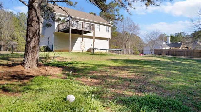 rear view of house featuring a yard, a trampoline, and fence