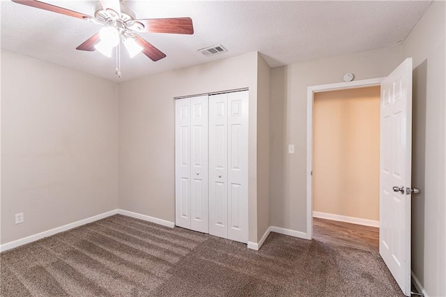 unfurnished bedroom with dark colored carpet, ceiling fan, and a closet