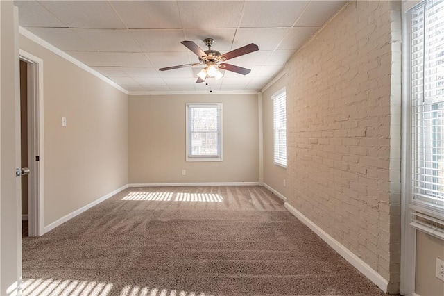 spare room featuring carpet, ceiling fan, ornamental molding, and brick wall