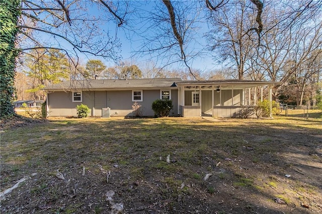 rear view of property featuring a lawn and central air condition unit