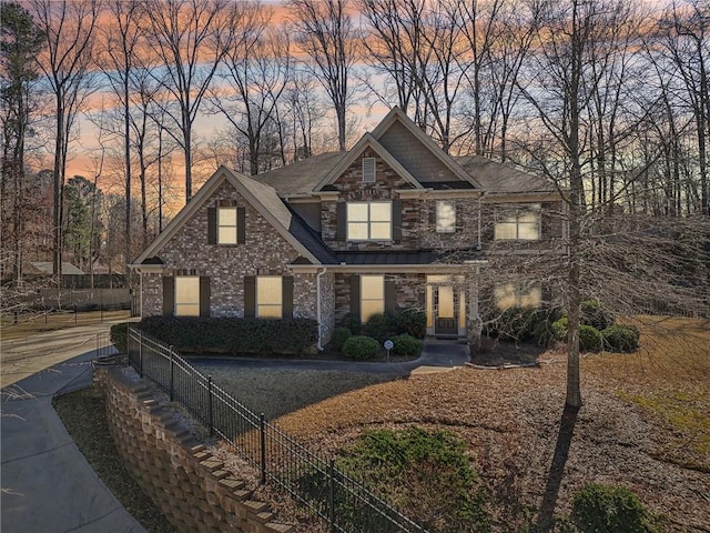 view of front of house featuring stone siding, a shingled roof, and fence