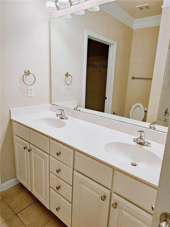 bathroom with toilet, tile patterned flooring, ornamental molding, and vanity