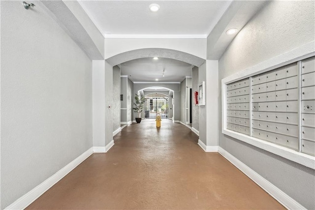 corridor with a mail area, concrete floors, and ornamental molding