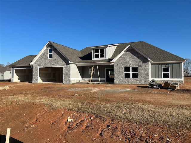 view of front of property with driveway, stone siding, board and batten siding, a shingled roof, and a garage