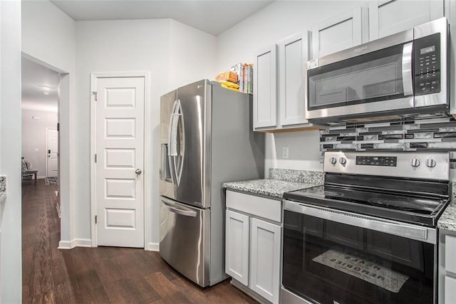 kitchen with white cabinetry, decorative backsplash, appliances with stainless steel finishes, dark hardwood / wood-style flooring, and light stone countertops