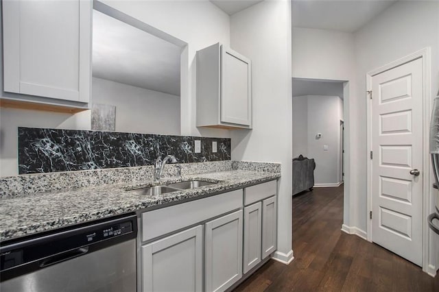 kitchen with light stone counters, sink, stainless steel dishwasher, dark wood-type flooring, and white cabinetry