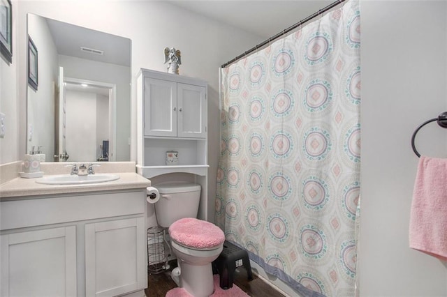 bathroom featuring walk in shower, vanity, hardwood / wood-style floors, and toilet